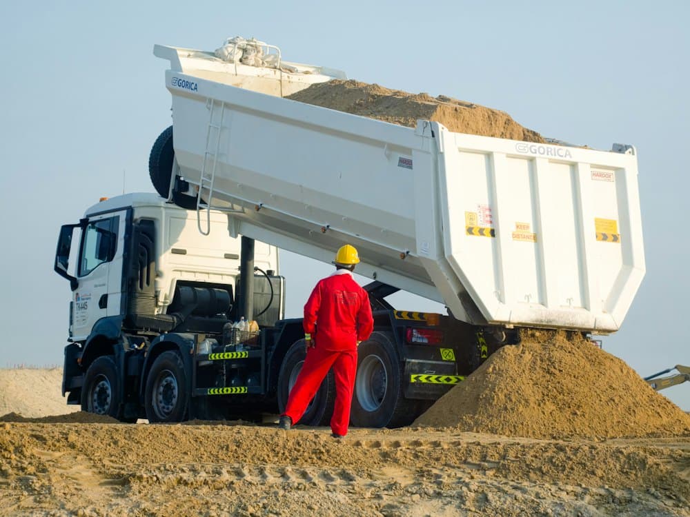 Camion benne déchargeant du sable sur un chantier
