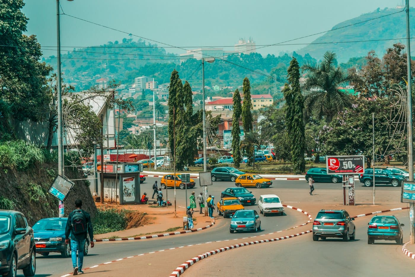 Rue de Yaoundé bordée de collines, avec ses taxis jaunes